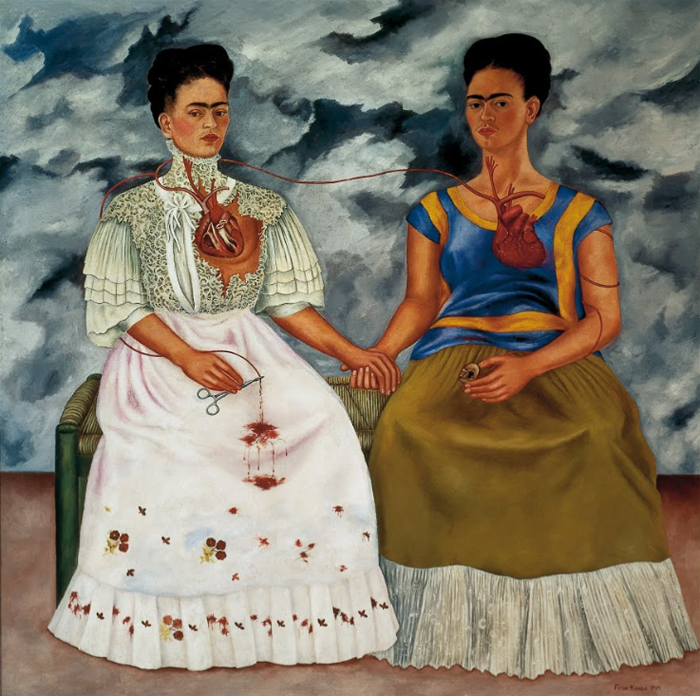 Painting of two seated women holding hands with exposed hearts connected by a vein, symbolizing inner emotional and cultural duality.